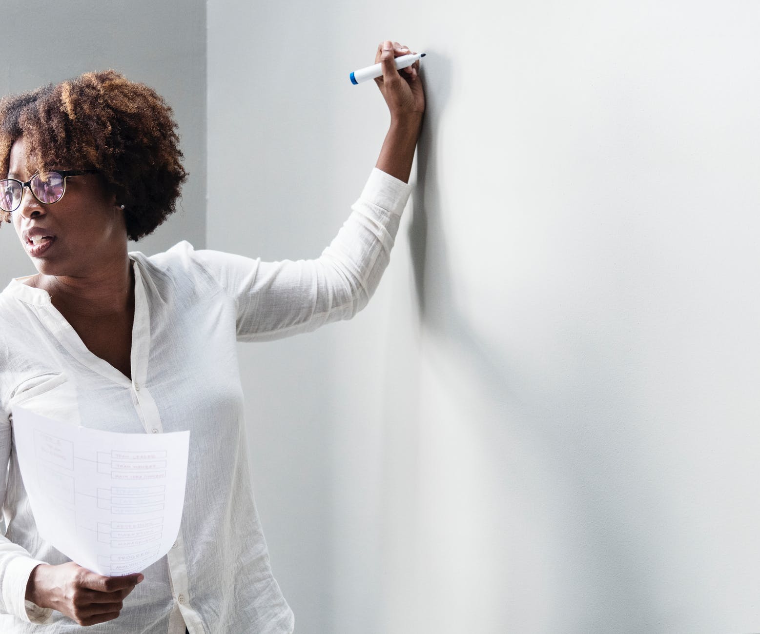 woman in white dress shirt holding blue permanent marker